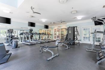 A spacious gym with a variety of equipment including treadmills, elliptical machines, and weight machines.